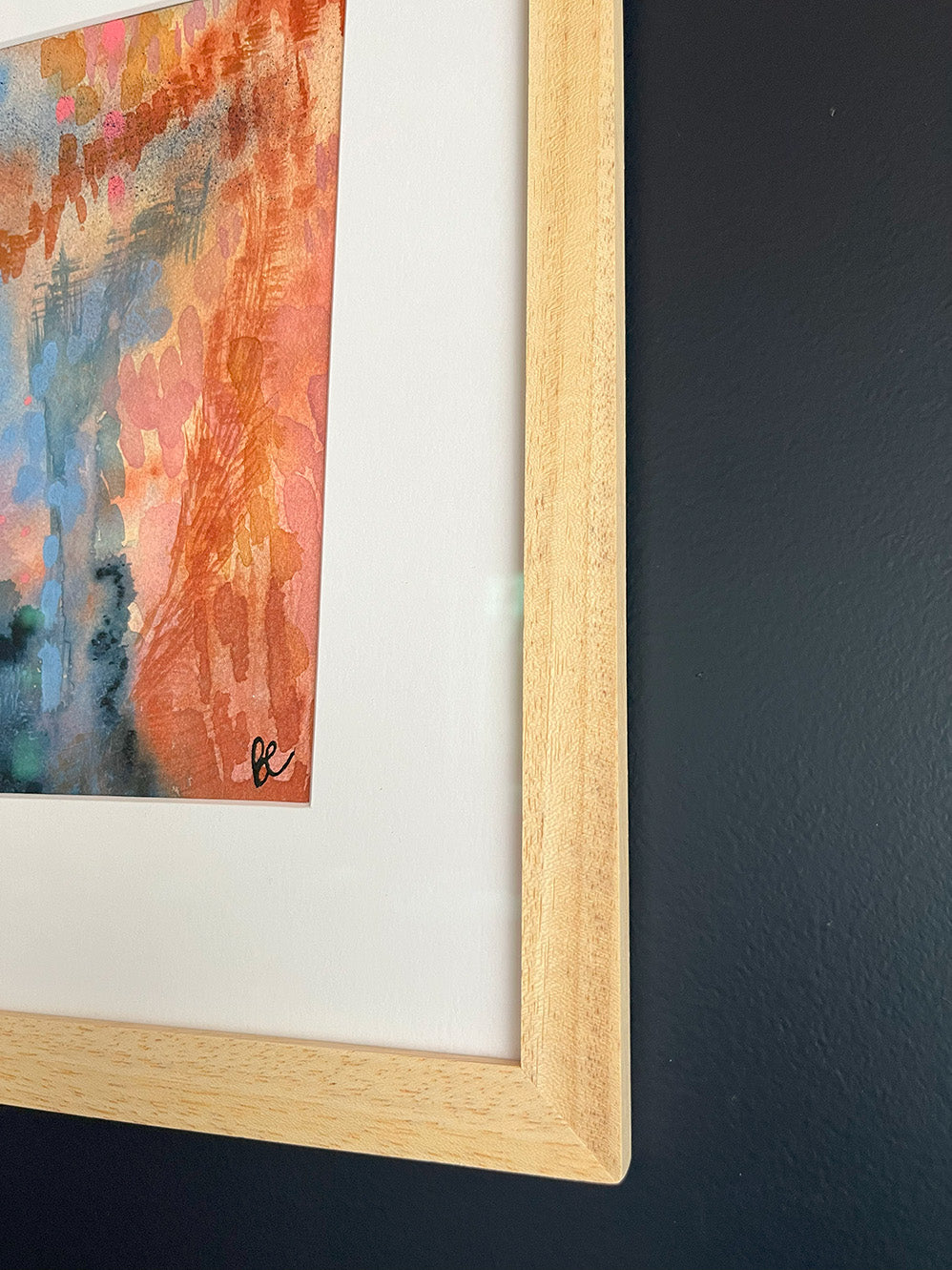 Close-up of Framed Watercolour Abstract called Conundrum hanged on a dark blue wall