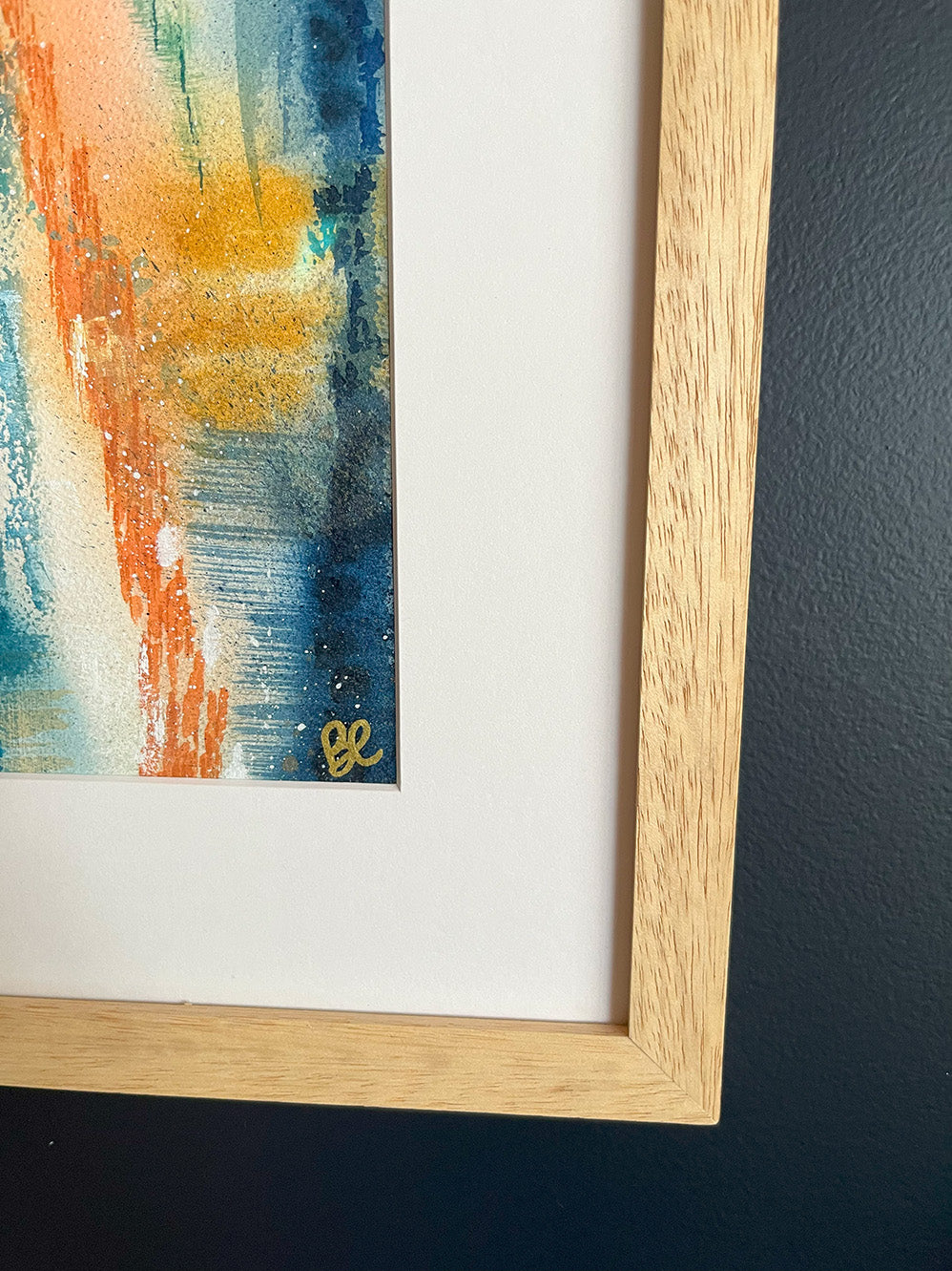 Close-up of Framed Watercolour Abstract called Yearning hanged on a dark blue wall