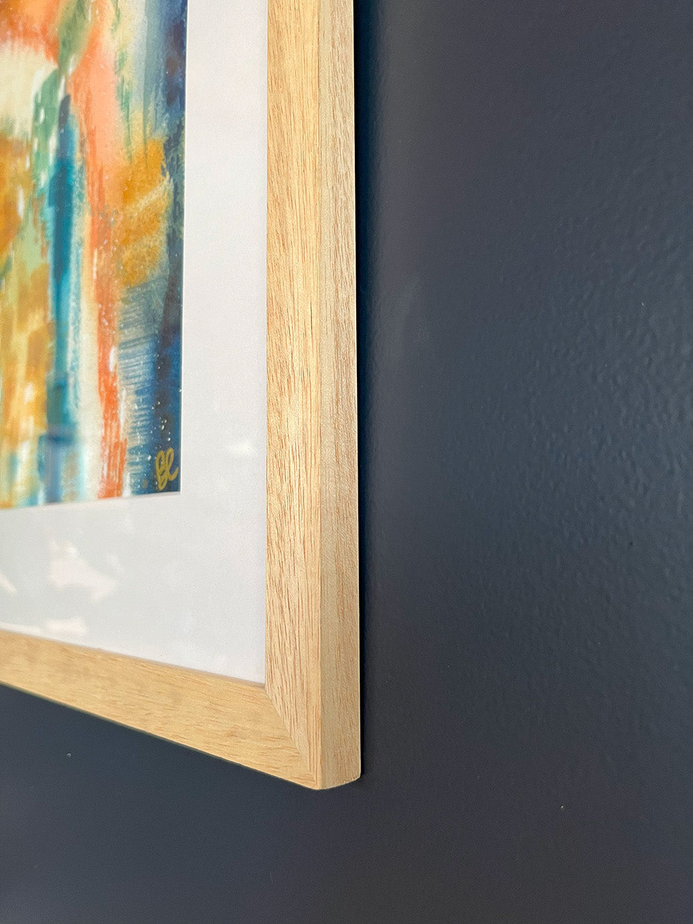 Close-up of Framed Watercolour Abstract called Yearning hanged on a dark blue wall