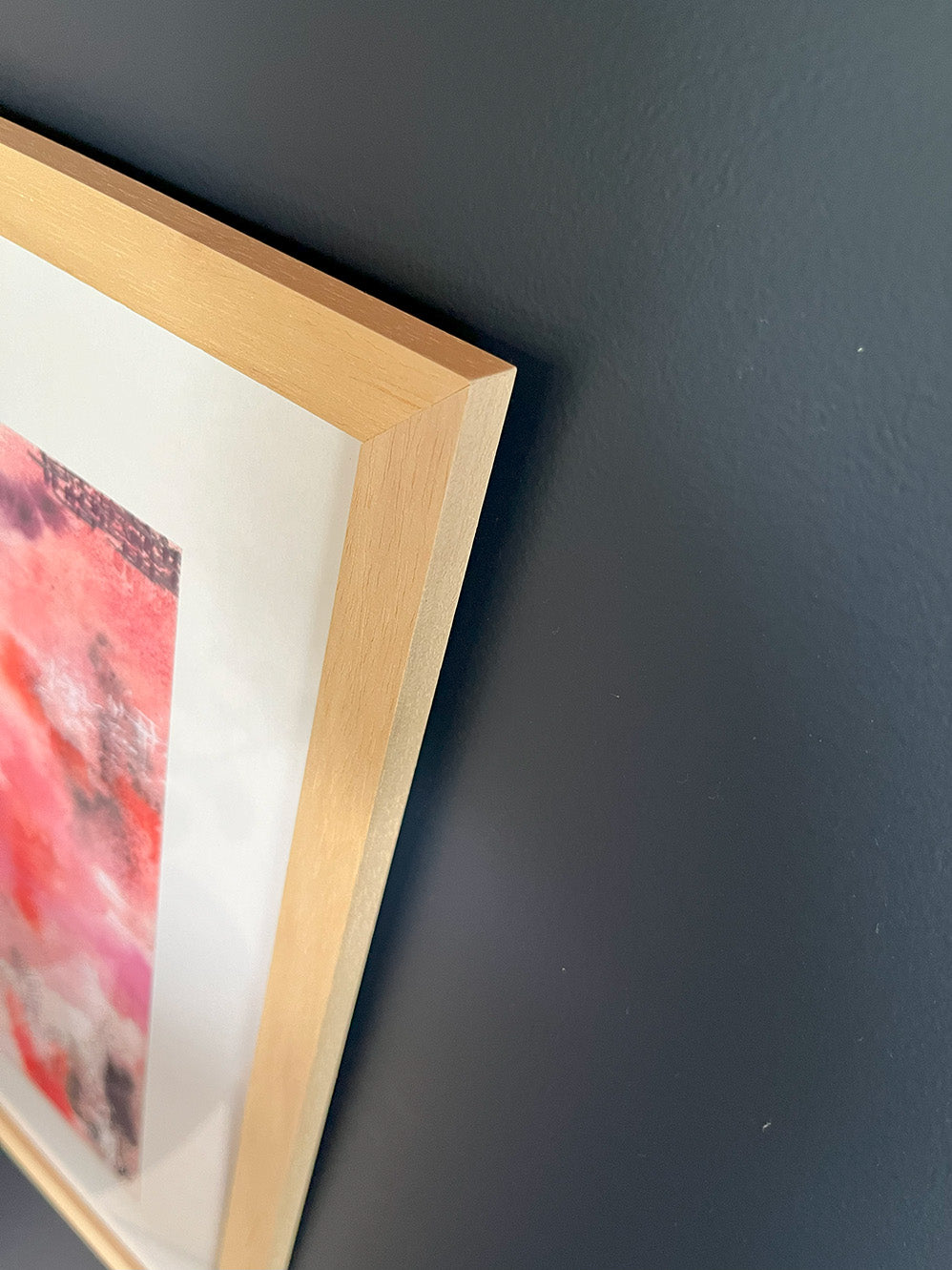 Close-up of Framed Watercolour Abstract called Uplift hanged on a dark blue wall