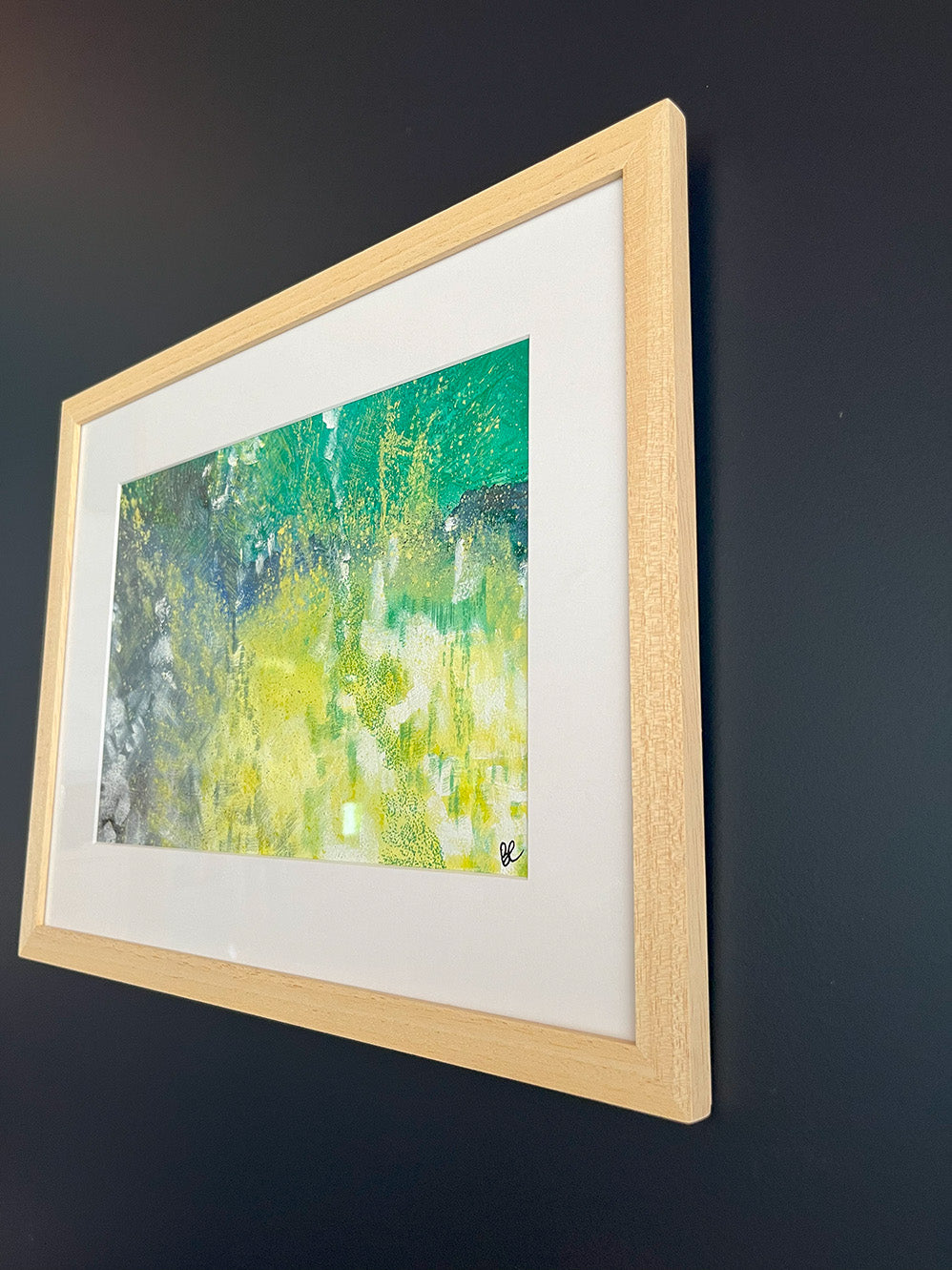 Close-up of Framed Watercolour Abstract called Tenacity hanged on a dark blue wall